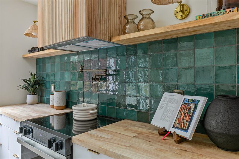 Kitchen detail with green zellige tile, butcher-block counters and open wood shelving
