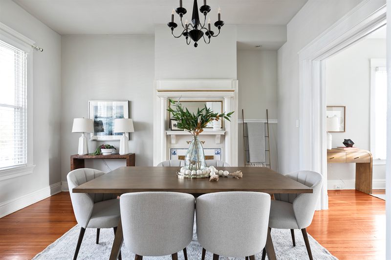 Dining room with a black chandelier, grey upholstered chairs and greenery on the table