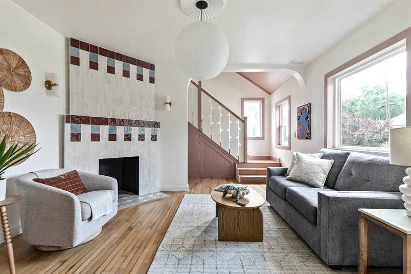 Living room with a tiled fireplace, globe pendant, grey sectional and woven wall discs