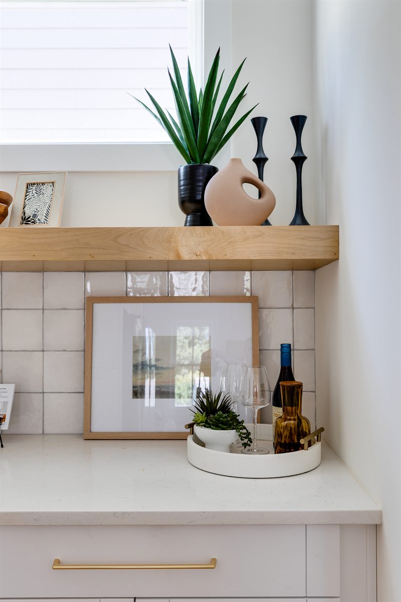 Maple floating shelf with a snake plant and candlesticks above a tray of glassware and framed art