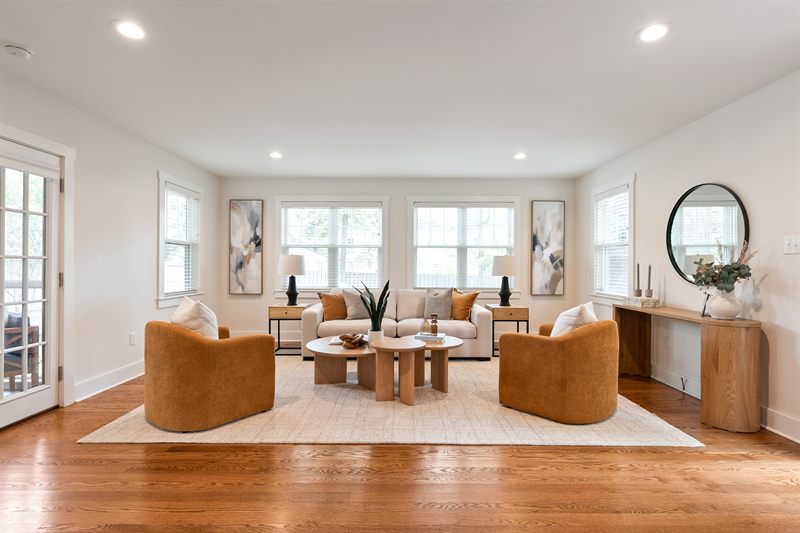 Living room with caramel swivel chairs and a cream sofa on a pale rug over oak floors